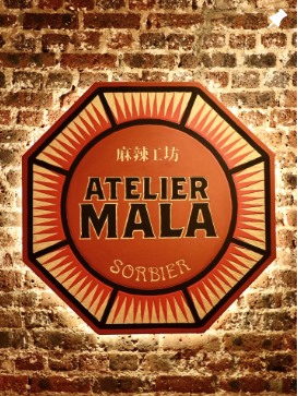 Enseigne Atelier Mala Sorbier sur un mur de briques